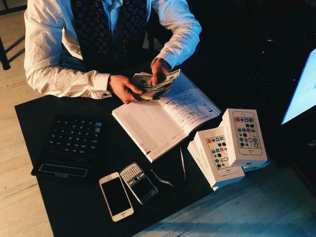 person counting money with smartphones in front on desk | Keys to High Commercial Real Estate Commissions – Part 1 | broker commission
