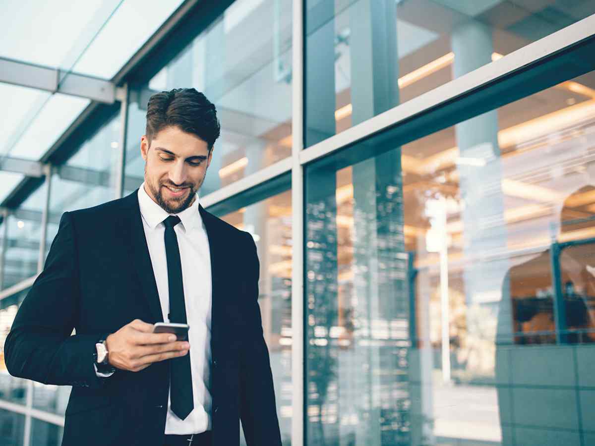 businessman using smartphone smiling | Keys to a Stronger Market Presence That You Can Get Right Now